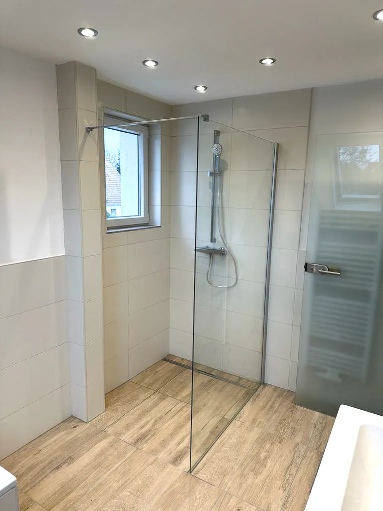 Sanierte bodengleiche Dusche mit transparenter Glastrennwand