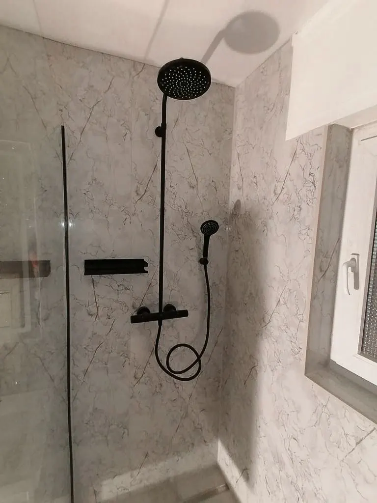 Sanierte Dusche mit schwarzen Armaturen und grifflosen Einbaumodulen