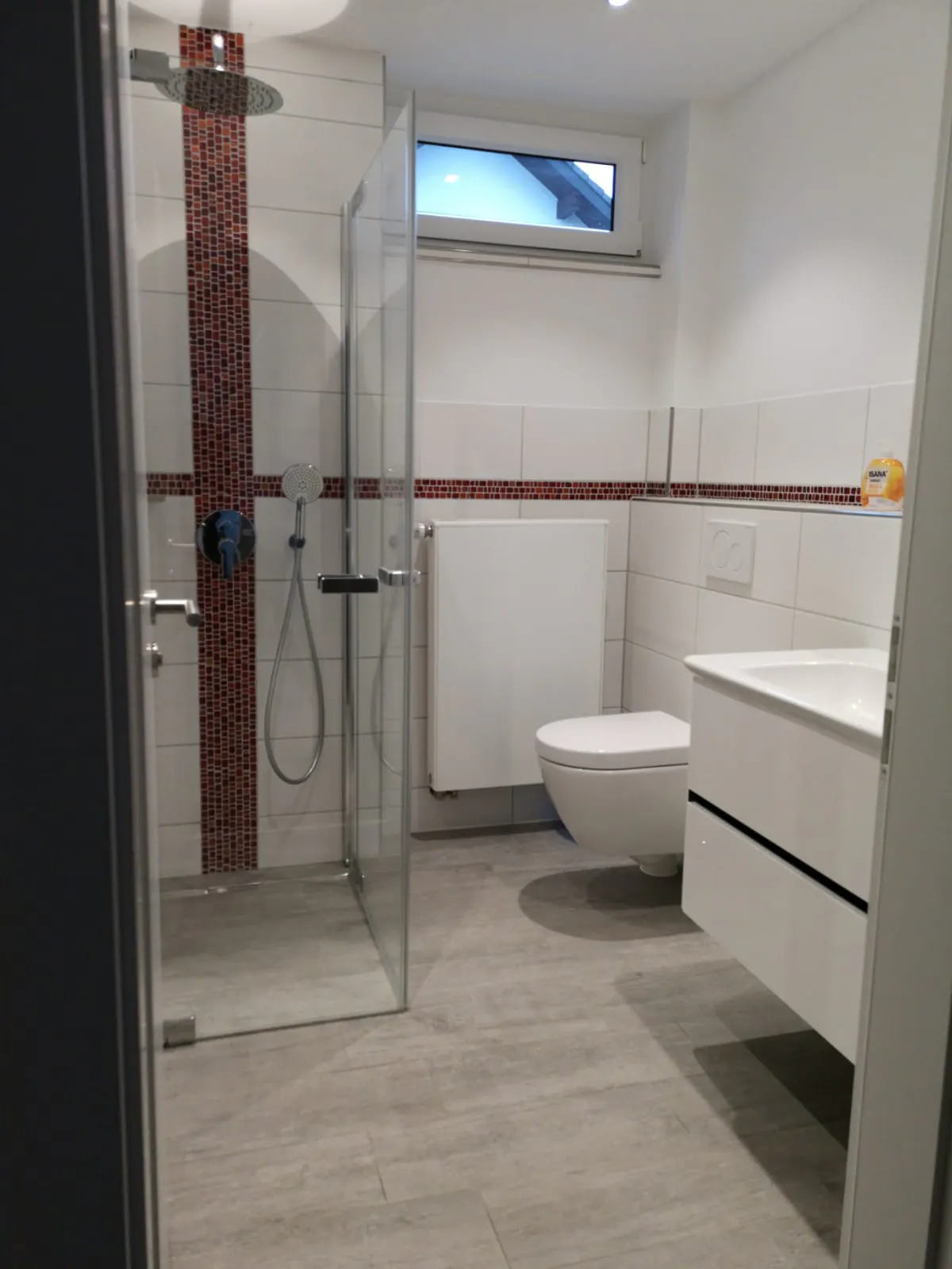 Saniertes Badezimmer mit roter Mosaikbordüre
