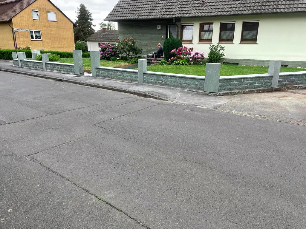 Sanierte Grundstücksmauer und Eingangsbereich eines Wohnhauses