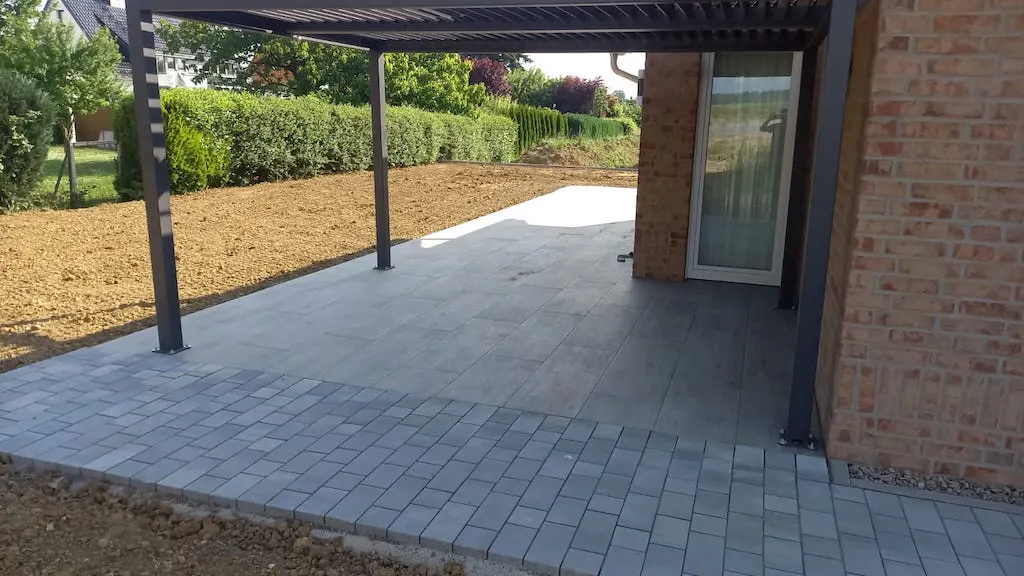 Gepflasterte Terrasse mit Überdachung an einem Wohnhaus