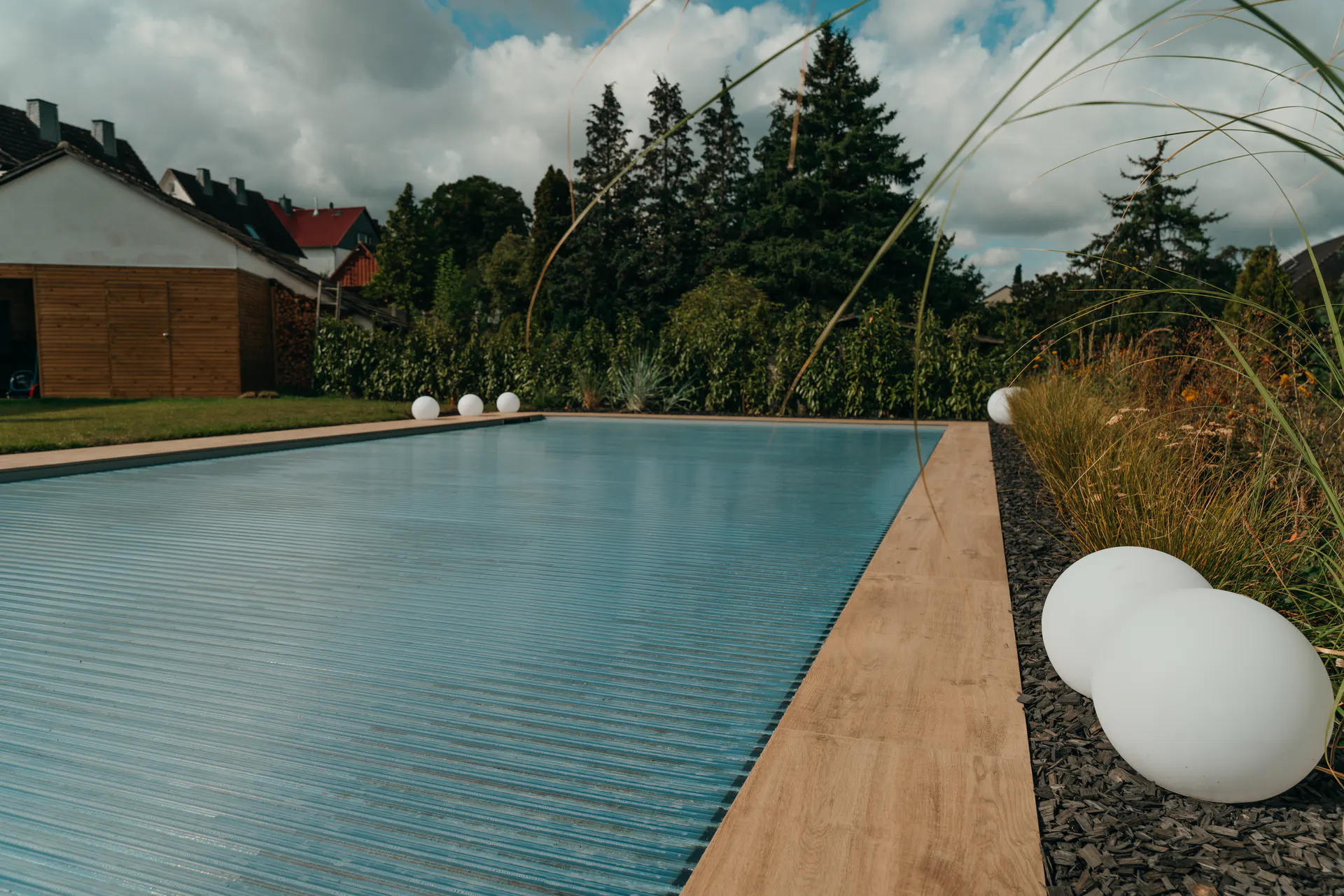 Pool mit heller Umrandung und moderner Gartengestaltung