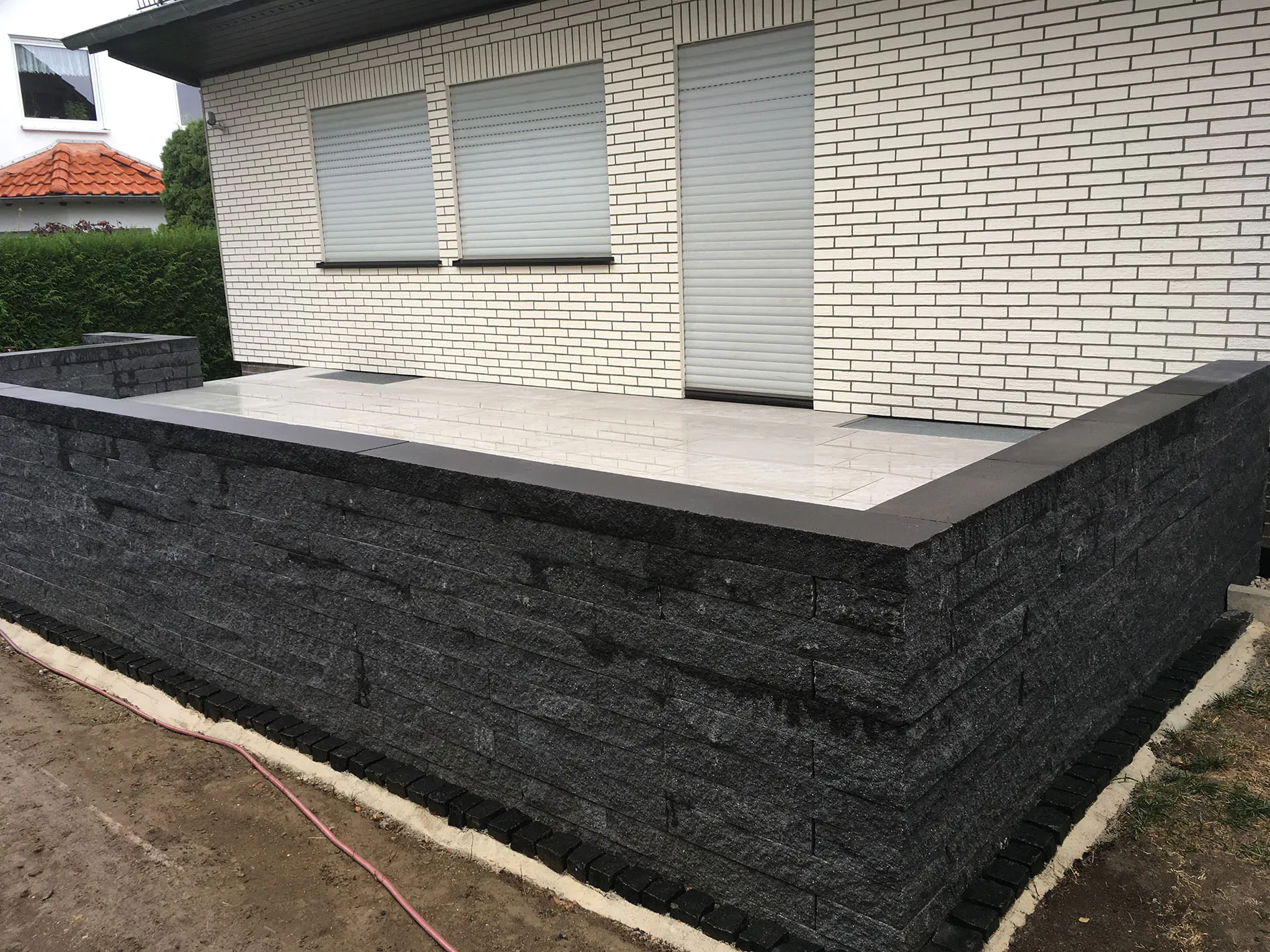Sanierte Terrasse mit heller Fläche und dunkler Einfassungsmauer
